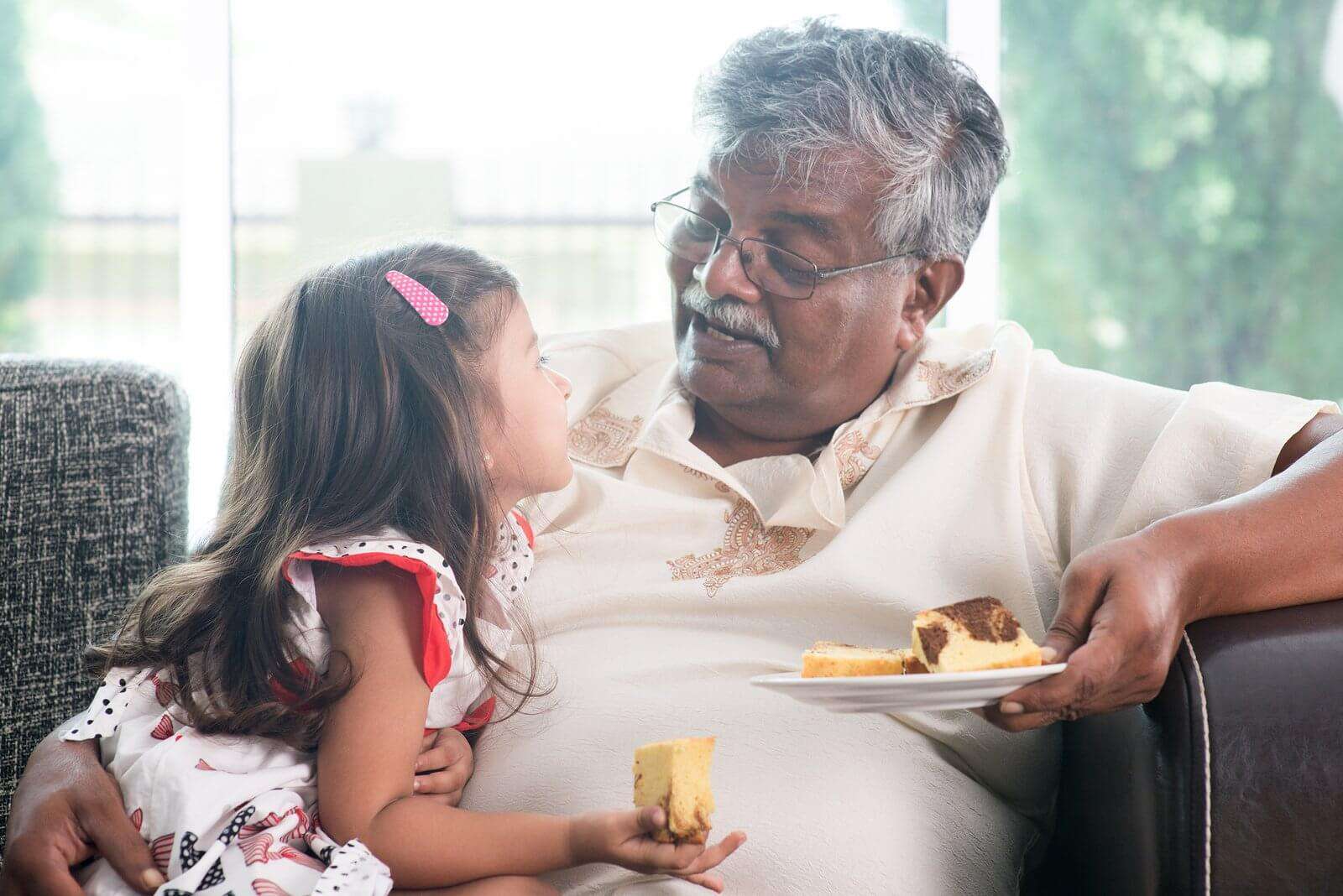 A grandfather eating with his grand daughter