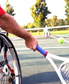 A man playing tennis in a wheelchair