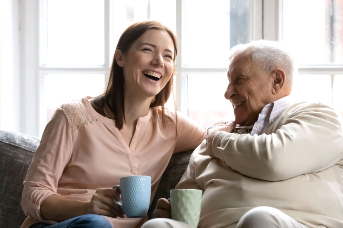 a caregiver daughter having a cup of hot beverage with her senior father .