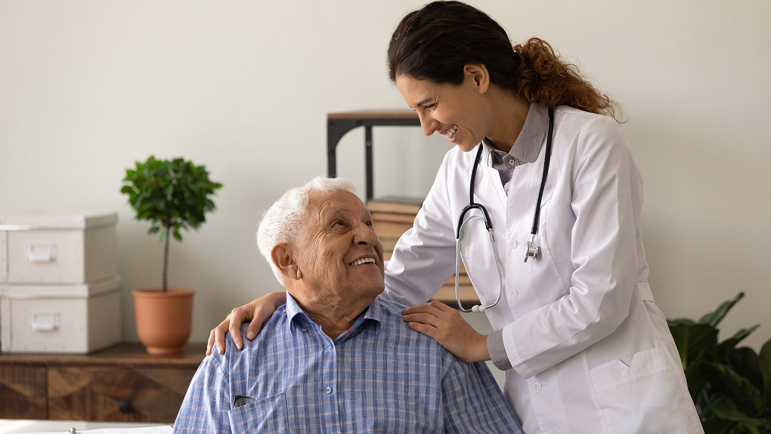 doc embrace shoulders of laughing old man sitting on chair at clinic office