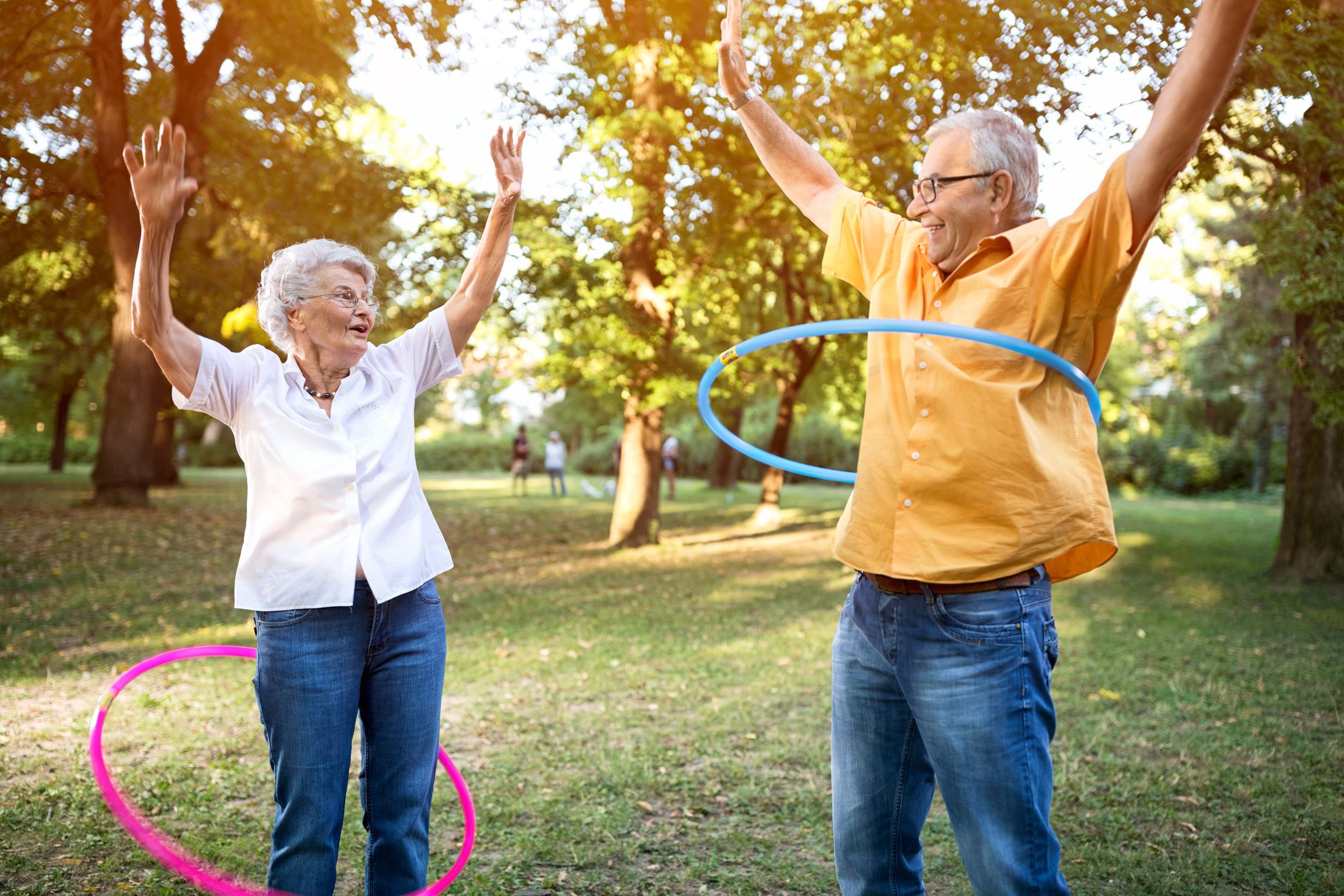 Two older people hula-hooping and enjoying their time in the sun