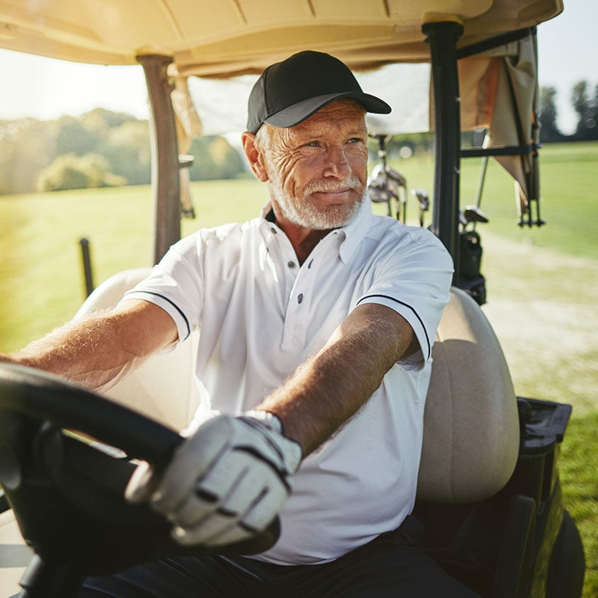 Senior man driving his golf cart on a fairway