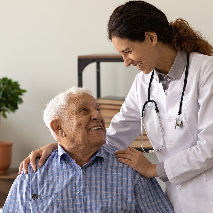 doc embrace shoulders of laughing old man sitting on chair at clinic office